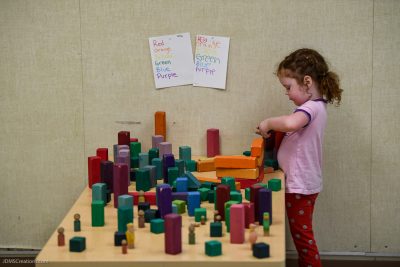 Young child plays with colorful blocks on a low children's worktable in a classroom.