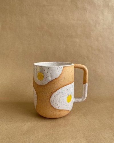 Handmade ceramic mug with two fried eggs drawn on it.