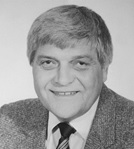 A black-and-white portrait of Dr. Bodemer wearing a textured suit jacket, a collared shirt, and a striped tie. The background is plain.