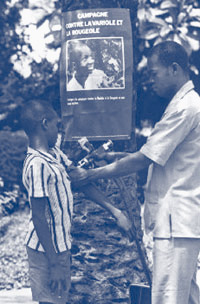 In the early 1970s, a boy receives a vaccination at an outdoor clinic in Africa.