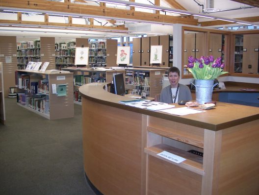 woman sitting behind reference desk next to bouquet of tulips