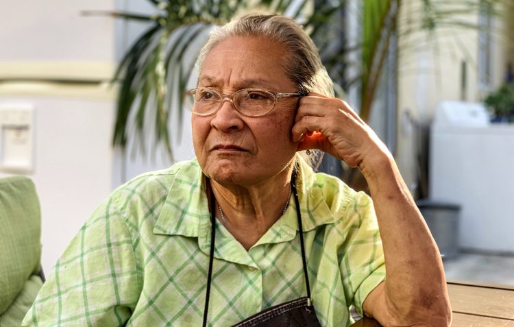 stoic looking Latina woman sitting and looking off camera