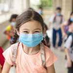 Young girl with braided hair and a mask on running.