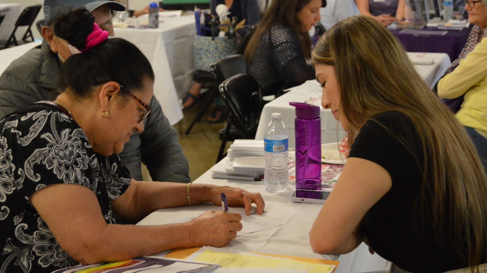 Three people sit at a table during a Brain Health fair to do cognitive testing.