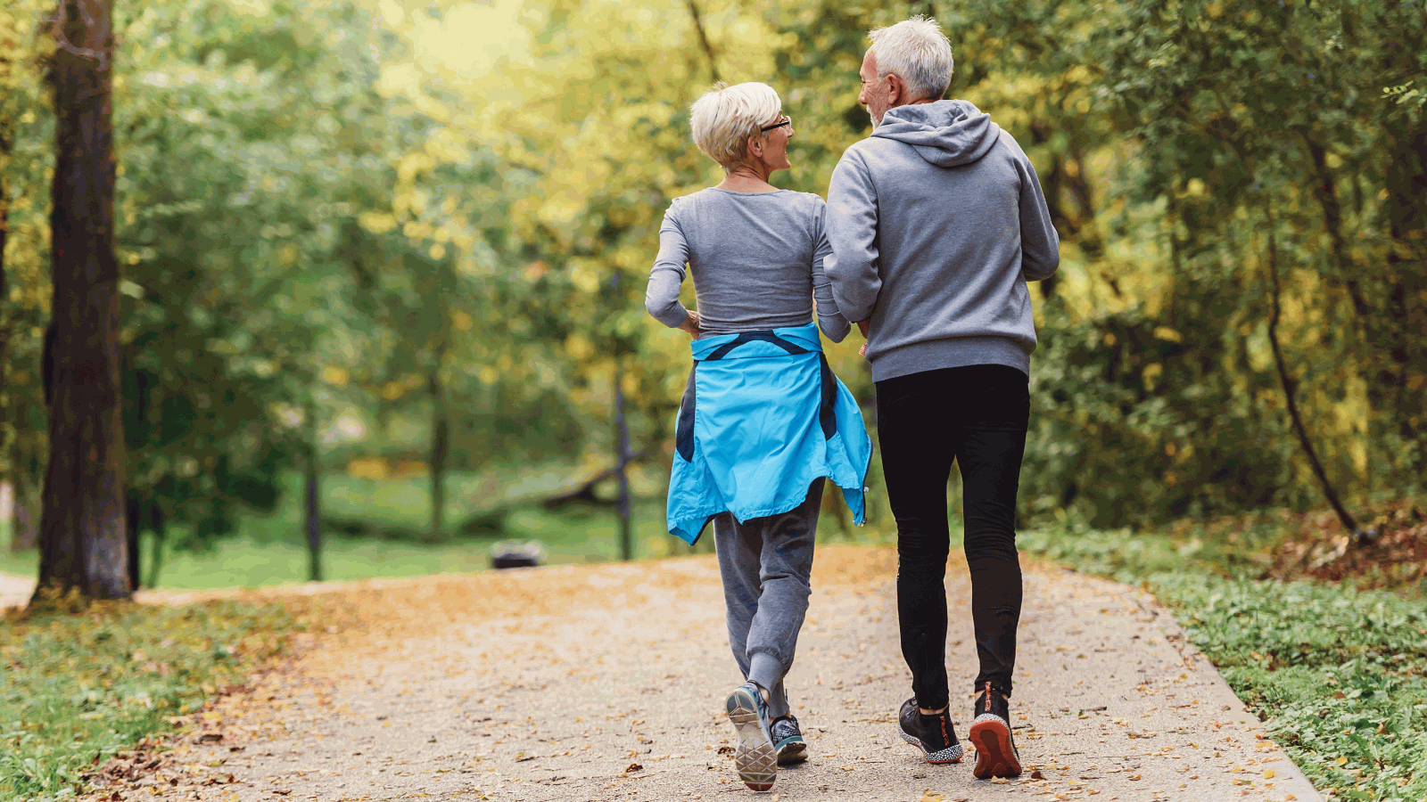 Older adult couple walks in a park.