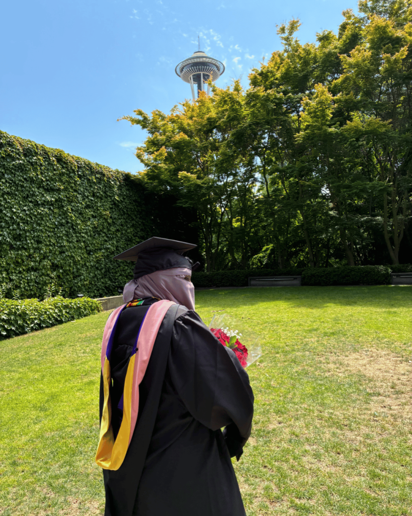 Samira Farah stands in front of the space needle in with her academic regalia.