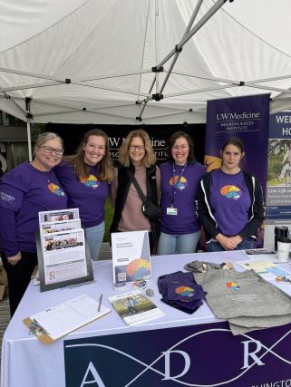 Five staff members stand at a resource table tent at an Alzheimer's awareness event
