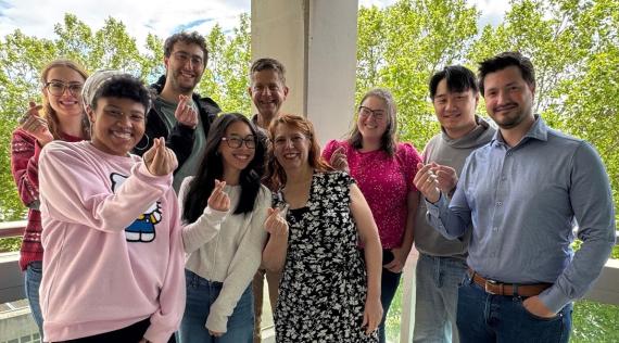 Nine young adults smile at camera