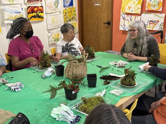 People creating moss balls at a table