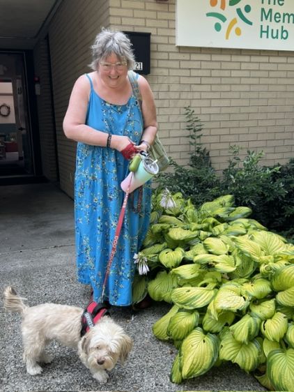 Woman in blue summer dress walking a service dog on a leash