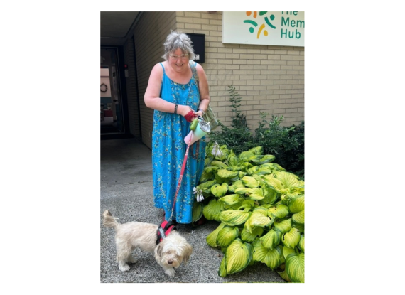 Woman in blue summer dress walking a service dog on a leash