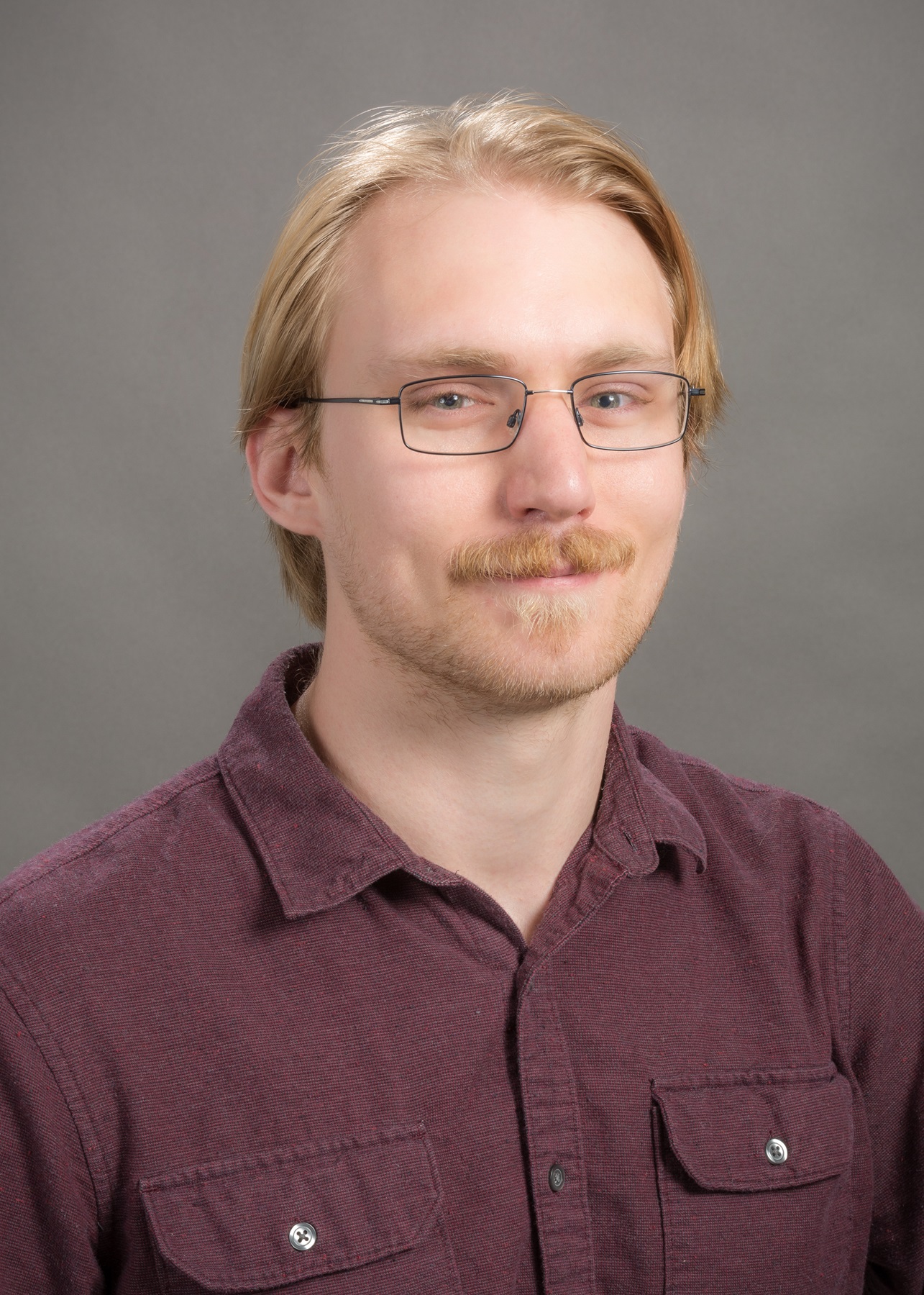 headshot of Jeremiah in wine colored collard shirt