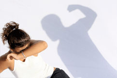 Girl in crouched position is shielding her face with her arm as a boy portrayed in silhouette stands over her with his arm raised and his fist clenched.