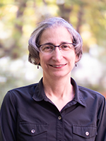 White woman with glasses and short gray hair smiling at camera.