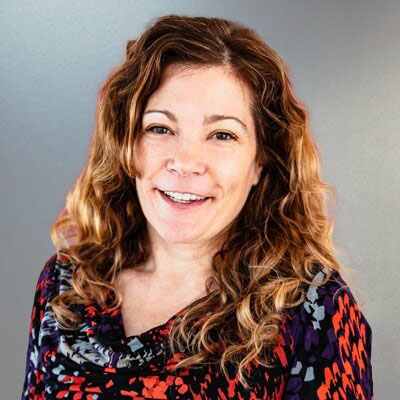 Smiling woman with long wavy hair.
