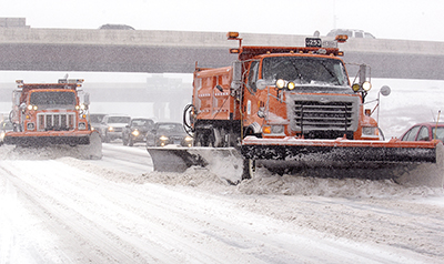 Snow plow trucks clearing the side of a highway