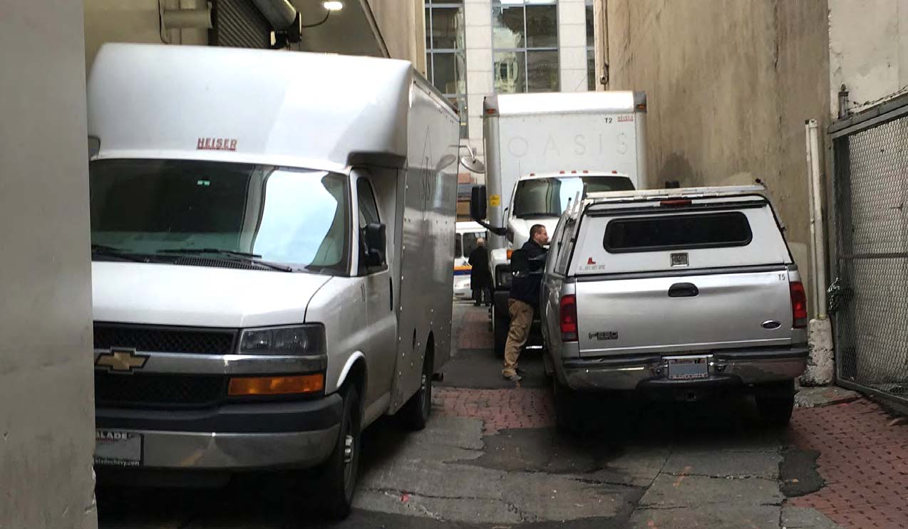 A Seattle business district alley crowded with cars and delivery trucks