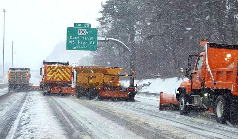 Snow plows on a highway during daytime snowfall