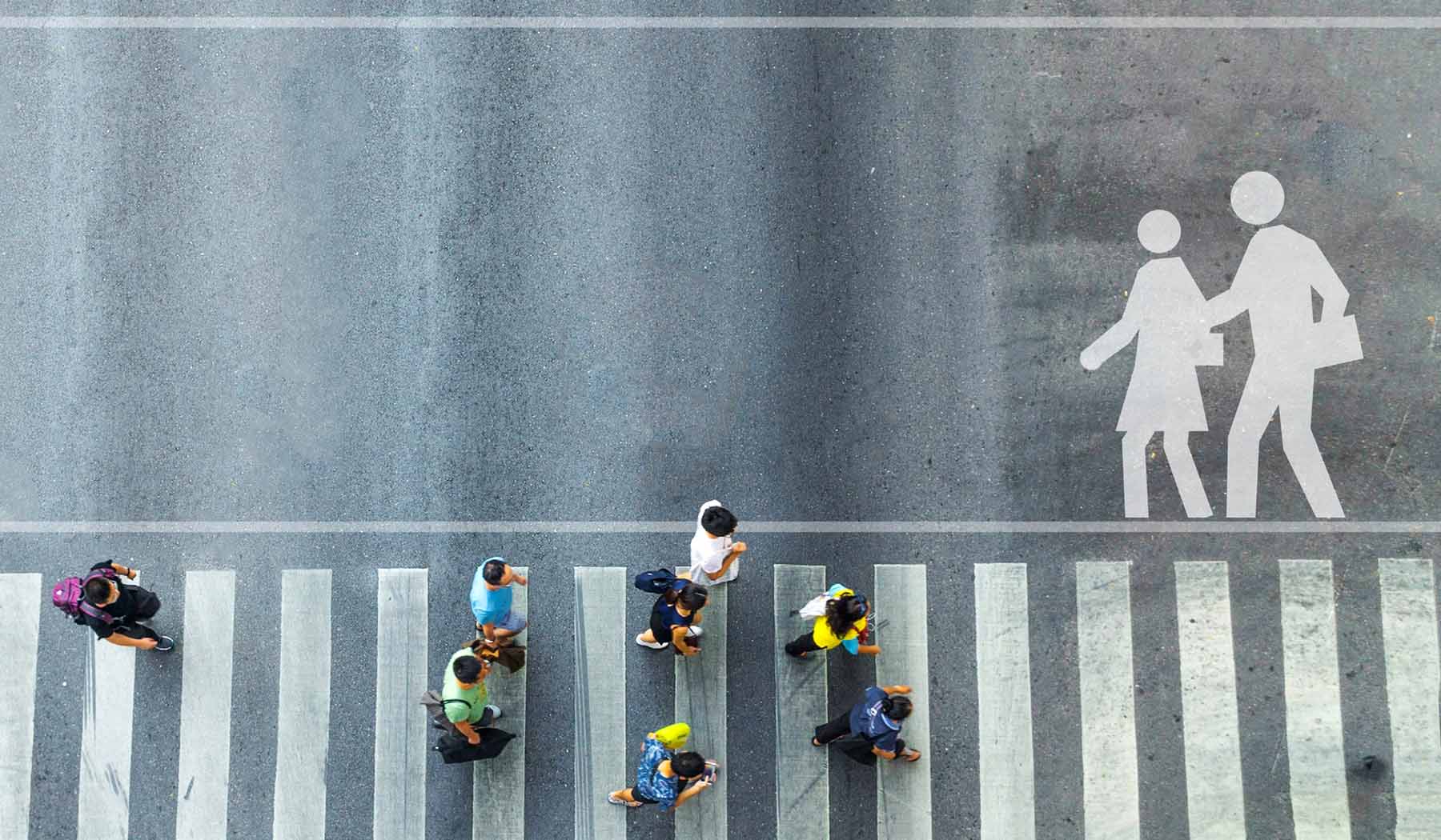Looking down from above at people crossing a white-striped crosswalk