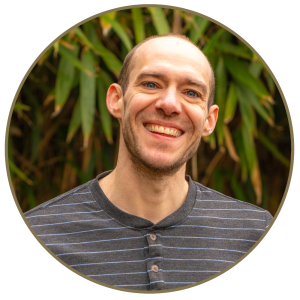 Dr. Brad Wagenaar, wearing striped shirt, smiling in front of bamboo