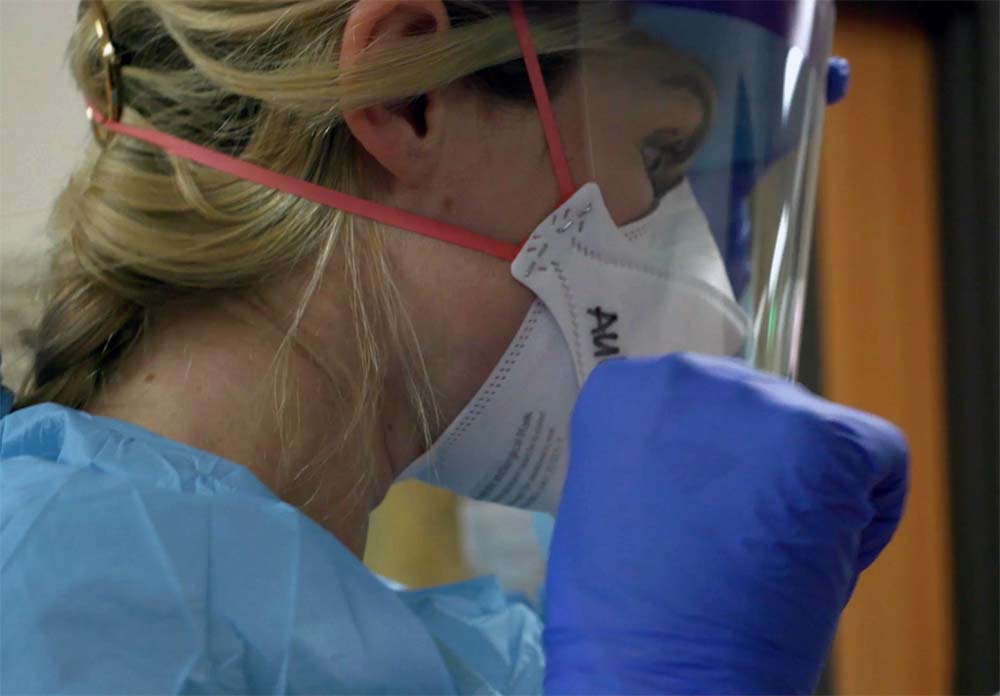 A nurse adjusts her PPE.