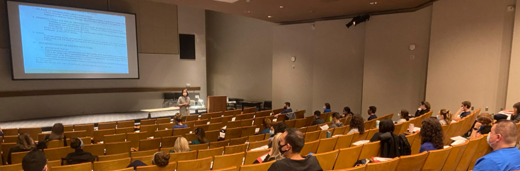 Nursing educator leading session in a large theater. Students are masked and socially-distanced.