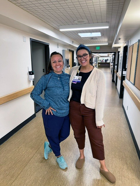 two nurses standing in the hallway of 1E