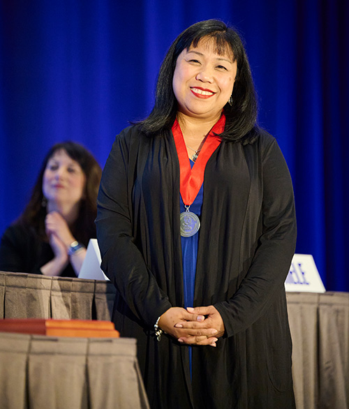 Nancy Colobong Smith wearing a medal and gown onstage
