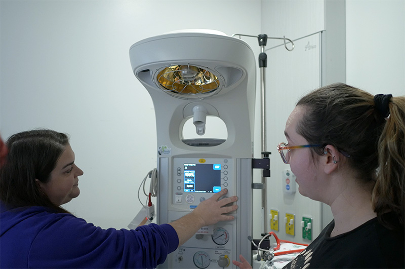 a nurse showing another nurse how to use a machine