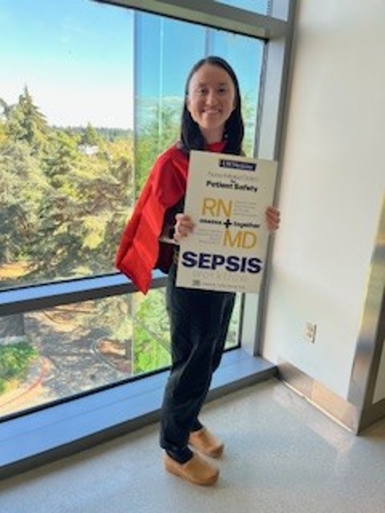 a nurse holding up a sepsis awareness poster