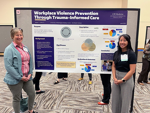 Poster presenters standing near a poster titled Workplace Violence Prevention Thrtough Trauma-informed Care