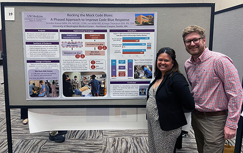 Poster presenter standing near poster titled Rocking the Mock Code Blues: A Phased Approach to Improve Code Blue Response