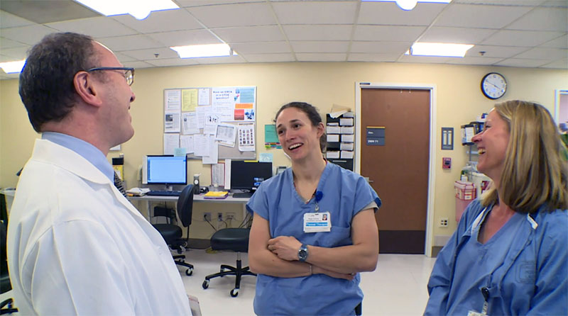 Two APRNs in conversation with a doctor. All are smiling.