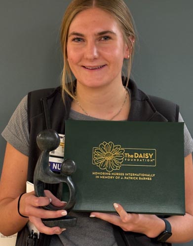 Audra Mary holding her DAISY award.