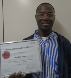 Modou Sowe holding his ROSE award.