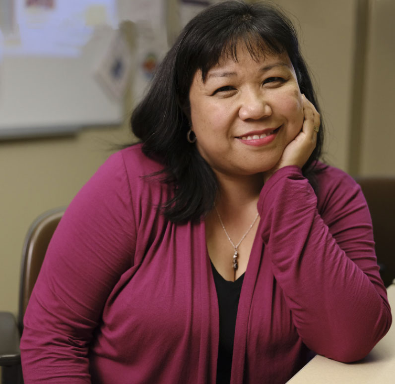 UWMC Nurse Nancy Colobong-Smith smiling and leaning on a table